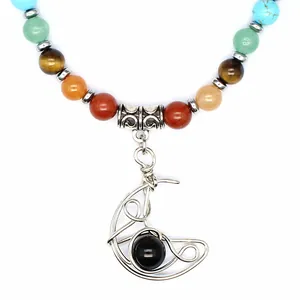 Primo piano del ciondolo a luna avvolto nel filo con pietra nera su collana di chakra.
