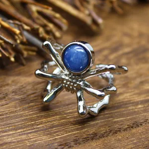 Macro view of a silver spider-shaped open ring featuring a blue natural stone inlay.