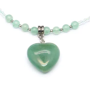 Macro detail of a heart-shaped green natural stone pendant on a beaded necklace strand
