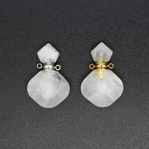 Detailweergave van twee kristallen etherische oliefleshangers in ruitvorm met goud- en zilveren hals.