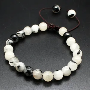 Detailed view of 8mm natural stone beads with unique black and white patterns on a woven bracelet