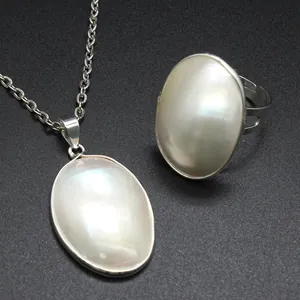 Detailed close-up of white iridescent Mabe pearl necklace pendant and matching ring set
