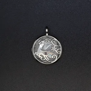 Macro detail of a silver reindeer locket pendant with a rose quartz stone inlay