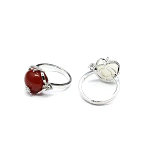 Vue détaillée de bagues argentées avec agate rouge et pierre blanche, sertissage floral.