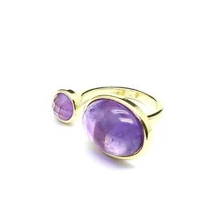 Gros plan d'une bague rétro dorée avec deux pierres naturelles violettes, design ouvert