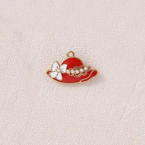 Detailansicht eines roten Emaille-Hutanhängers mit weißer Schleife und Perlen für DIY-Schmuck