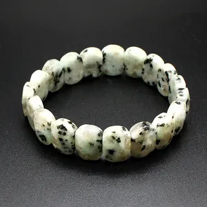Macro detail of natural faceted Dalmatian Jasper stone beaded bracelet on black surface