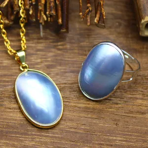 Detail of iridescent blue Mabe pearl pendant and ring set on wooden background