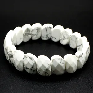Macro shot of a white faceted howlite bracelet with gray veins on black background