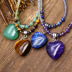 A macro detailed view showing four heart-shaped natural stone necklaces on a rustic wood surface