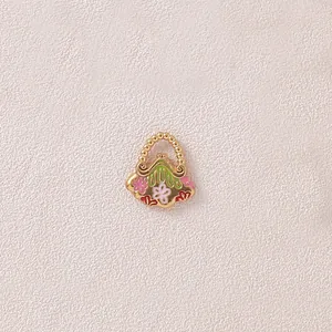 Detailansicht eines vergoldeten Handtaschen-Anhängers mit bunten Emaille-Blumen.
