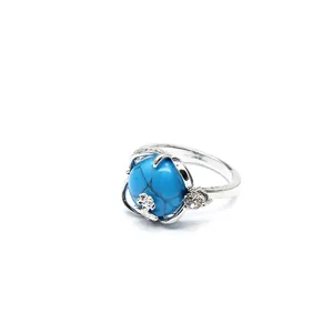 Gros plan d'une bague argentée avec une pierre turquoise et un motif floral délicat.