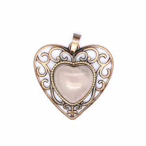 Detail of vintage bronze-tone heart pendant featuring intricate filigree and central pink stone
