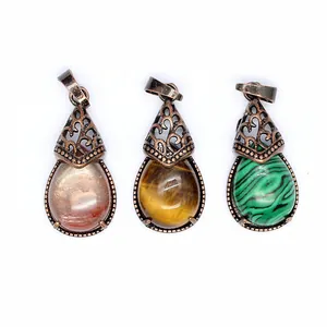 Macro detail of three vintage teardrop natural stone pendants featuring filigree metal caps