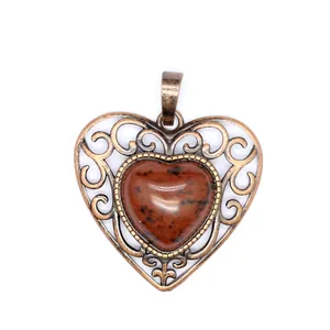 Macro detail of a vintage heart pendant with brown stone and bronze filigree