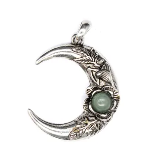 Primer plano de colgante de luna plateada vintage con hojas grabadas y piedra verde.
