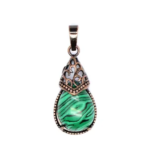 Detailed view of a vintage teardrop green stone pendant with ornate bronze filigree.