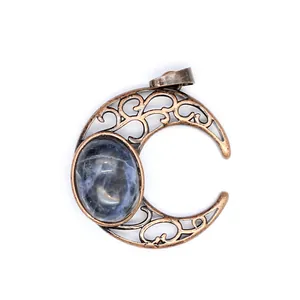 Detailed close-up of antique copper crescent moon pendant with natural blue sodalite stone