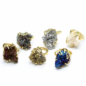 Close-up detail of various colorful natural druzy crystal rings with elegant gold plating