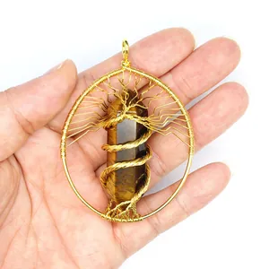 Handheld detail of a gold wire wrapped tree of life pendant with tiger's eye stone