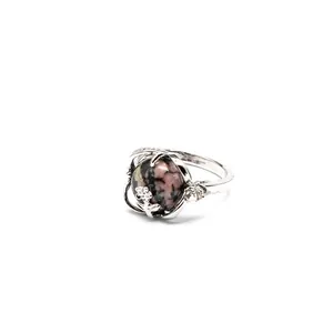 Vue détaillée d'une bague en argent avec pierre naturelle rose et noire et motif fleur.