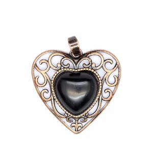 Close-up detail of vintage style hollow heart pendant featuring a polished black stone