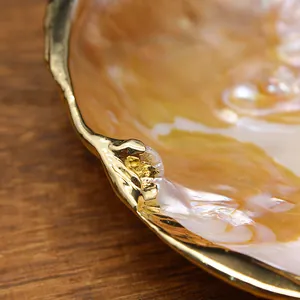 Macro detail view of a natural freshwater pearl shell tray featuring elegant gilded gold edges.