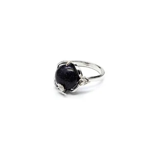Gros plan d'une bague argentée ouverte avec pierre de soleil bleue et motifs floraux