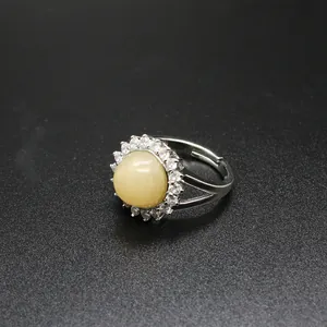 Close-up of adjustable silver-toned ring with round yellow stone and micro-paved crystals