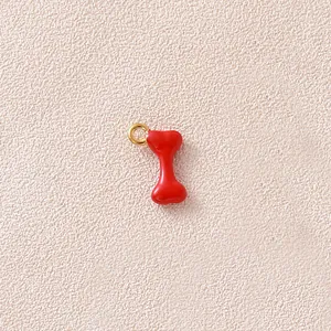 Nahaufnahme eines winzigen roten Knochenanhängers mit goldenem Ring für DIY-Schmuck