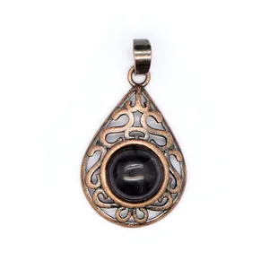 Macro view of a vintage bronze teardrop filigree pendant with a dark spherical natural stone
