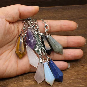 Detailed macro view of various hexagonal natural stone pendulum pendants on silver chains