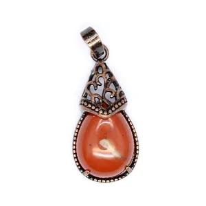 Macro detail of retro teardrop-shaped red agate pendant with ornate bronze filigree