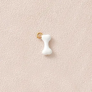 Makro-Detail des weißen Emaille-Knochenanhängers mit vergoldetem Edelstahlring für Schmuck