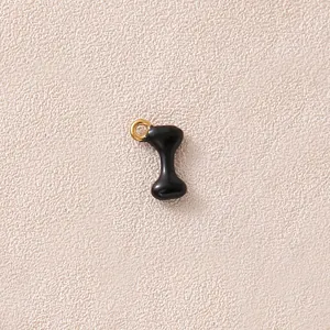 Detaillierte Nahaufnahme eines schwarzen Emaille-Knochenanhängers mit einem vergoldeten Ring.