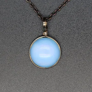 Close-up of light blue round stone pendant with vintage wire-wrapped detail