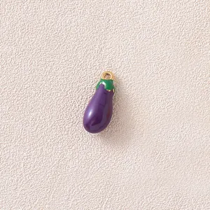 Macro view of a purple 3D eggplant charm with gold loop on textured background.