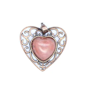 Close-up view of a vintage hollow heart-shaped pendant featuring a natural pink stone inlay