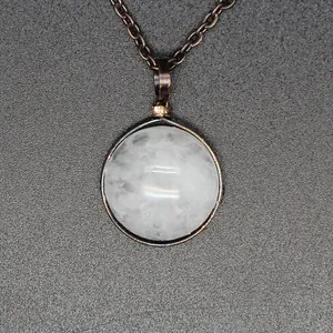Macro detail of a natural white stone pendant with retro metal wrap design on chain.