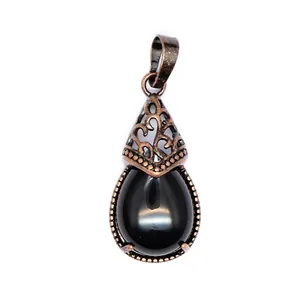 Macro view of a teardrop black agate pendant with vintage bronze filigree detail