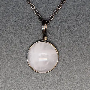 Close-up of vintage necklace featuring a round rose quartz stone pendant