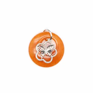 Vue détaillée d'un pendentif en agate orange avec un motif papillon en argent ciselé.