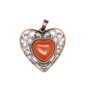 Detailed view of vintage bronze hollow heart pendant with red natural stone inlay