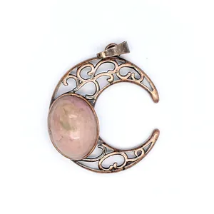 Close-up detail of an antique crescent moon pendant featuring pink natural stone inlay