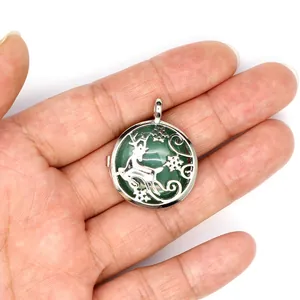 Close-up shot of a silver holy deer locket pendant with a green stone held in hand for scale