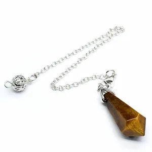 Macro view of a hexagonal tiger eye stone pendulum pendant with a silver chain.