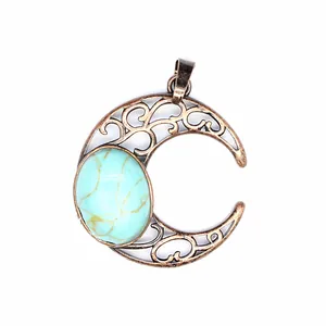 Macro view of a vintage bronze hollow-out crescent moon pendant with oval turquoise.