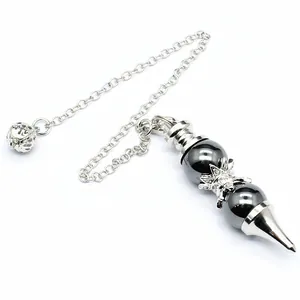 Macro view of a dowsing pendulum featuring dark grey spheres and a silver cone tip