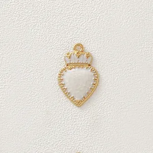 Primo piano dettagliato di un ciondolo a cuore dorato vintage con corona e smalto bianco