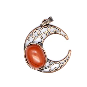 Close-up detail of an antique hollow crescent moon pendant with red natural stone inlay.